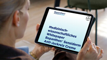 Eine Frau schaut sich auf einem Tablet das Whitepaper zu Bepanthen Sensiderm Anti-Juckreiz Creme an.