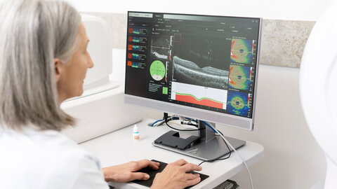 Eine Ärztin sitzt vor einem Computerbildschirm und schaut sich eine Darstellung der menschlichen Haut an