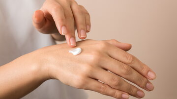 Nahaufnahme: eine Frau befeuchtet ihre Hand mit Feuchtigkeitscreme