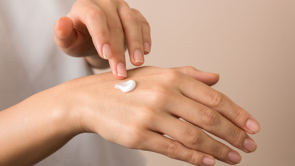 Nahaufnahme: eine Frau befeuchtet ihre Hand mit Feuchtigkeitscreme